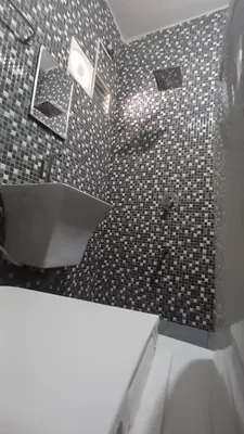 a bathroom with a black and white tiled wall at SHI's Thulasi 2BHK in Coimbatore Near to Karpagam College, Palakkad Highway, Rathinam College and More in Coimbatore