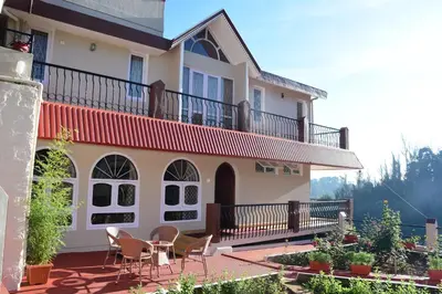 a house with a balcony and tables and chairs at Rosewood 1 in Ooty
