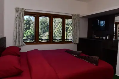 a bedroom with a red bed and windows at Rosewood 1 in Ooty