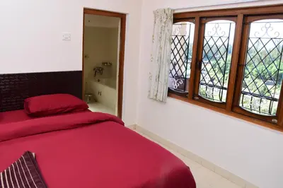 a bedroom with a red bed and a window at Rosewood 1 in Ooty
