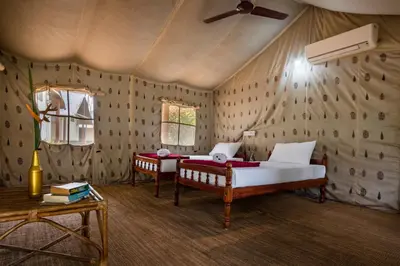 a bedroom with two beds and a ceiling fan at Amritara Riverside Camp in Thattakād
