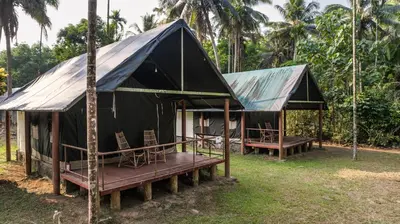 a tent with chairs and tables in the grass at Amritara Riverside Camp in Thattakād