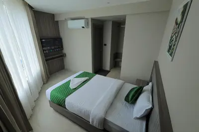 a bedroom with a bed with green sheets and pillows at Mount Land in Sultan Bathery