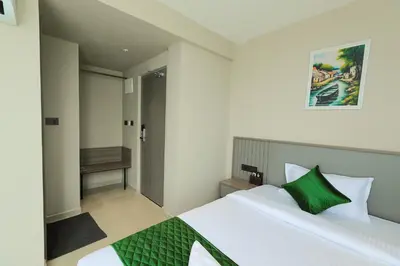 a bedroom with a large white bed with a green pillow at Mount Land in Sultan Bathery