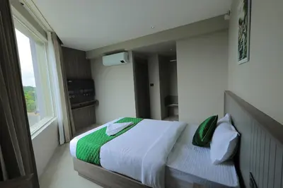 a bedroom with a bed with white and green sheets at Mount Land in Sultan Bathery