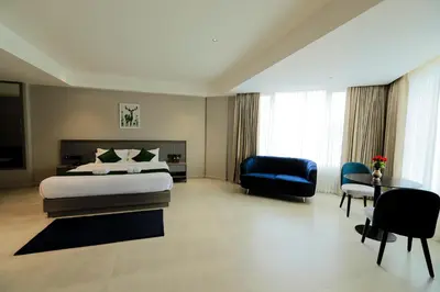 a large bedroom with a bed and a blue chair at Mount Land in Sultan Bathery