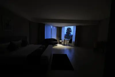 a dark room with a bed and a chair and a window at Mount Land in Sultan Bathery