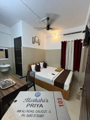 a hotel room with a bed and a table at Priya lodge in Kozhikode