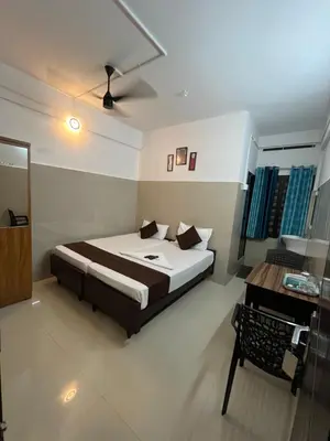 a bedroom with a bed and a desk in it at Priya lodge in Kozhikode