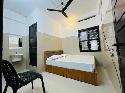 a bedroom with a bed and a chair and a sink at Priya lodge in Kozhikode