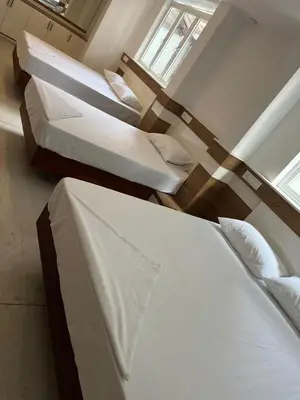 a room with three beds and a window at Welcome Hotels in Trichūr
