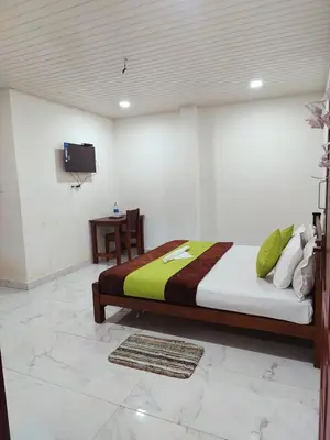 a bedroom with a bed and a tv on a wall at Chaithanya Illam in Marayoor