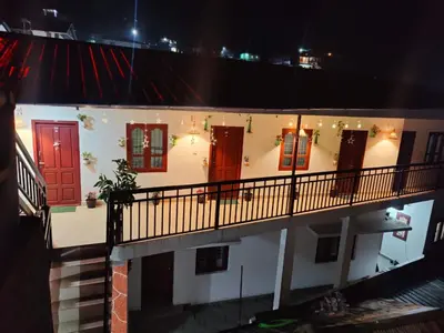 a building with red doors and a balcony at night at Chaithanya Illam in Marayoor