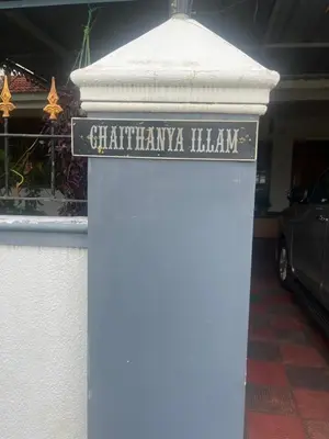 a sign on a column in front of a building at Chaithanya Illam in Marayoor