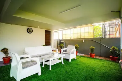 a patio with white chairs and a table and grass at Elite Enclave - Spark - 2BHK Luxury Serviced Apartment in Mysore