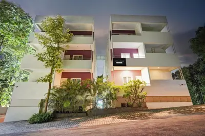 a white building with trees in front of it at Super Townhouse Hebbal Mysore in Mysore