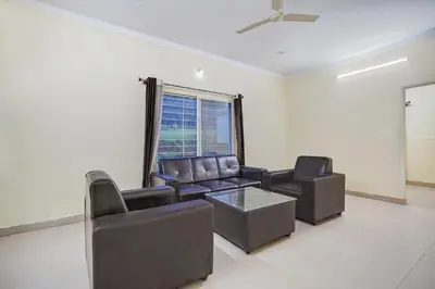 a living room with leather furniture and a window at Super Townhouse Hebbal Mysore in Mysore