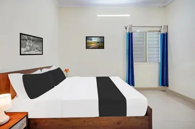 a bedroom with a black and white bed with blue curtains at Super Townhouse Hebbal Mysore in Mysore
