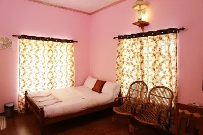 a bedroom with a bed with two chairs and a window at County Pep in Wayanad