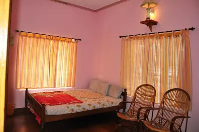 a bedroom with a bed with two chairs and a window at County Pep in Wayanad