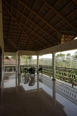 a patio with a table and chairs on a balcony at Dhara Dhvani Getaway Homes in Tindummal