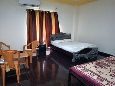 a room with a bed and a chair and a window at Govinda Krishna Comforts in Mysore