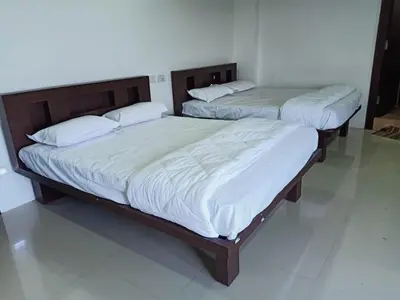 two beds in a bedroom with white sheets and pillows at Govinda Krishna Comforts in Mysore