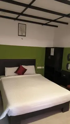 a bedroom with a white bed with a red pillow at JUNGLE VALLEY AYURVEDIC SPa RESORT in Meppādi