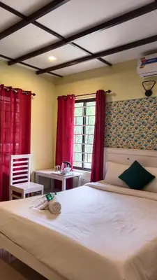 a bedroom with a bed with red curtains and a desk at JUNGLE VALLEY AYURVEDIC SPa RESORT in Meppādi