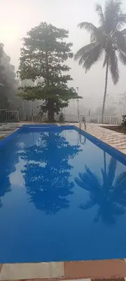 a blue swimming pool with palm trees in the background at JUNGLE VALLEY AYURVEDIC SPa RESORT in Meppādi