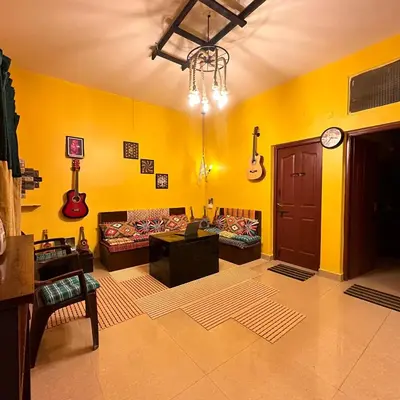 a living room with yellow walls and guitars on the wall at Rastafari - The Backpackers Hostel in Ooty
