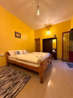 a bedroom with a large bed with yellow walls at Rastafari - The Backpackers Hostel in Ooty