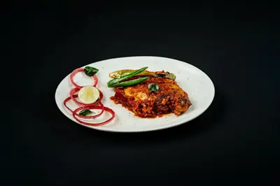 a white plate with food on a black table at Vedic Village Retreat Kodungallur in Cochin
