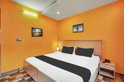 a bedroom with a large bed with orange walls at Super Collection O Kushal Nagar Near KSRTC Bus Stand in Madikeri