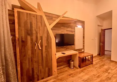 a room with a wooden wall with a tv and a desk at AJ Gable Clouds Ooty by VOYE HOMES - Serene Stay Near Avalanche Emerald Lake in Ooty