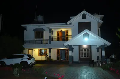 a white house at night with a car parked in front at Bridge Point Home Stay in Kushālnagar