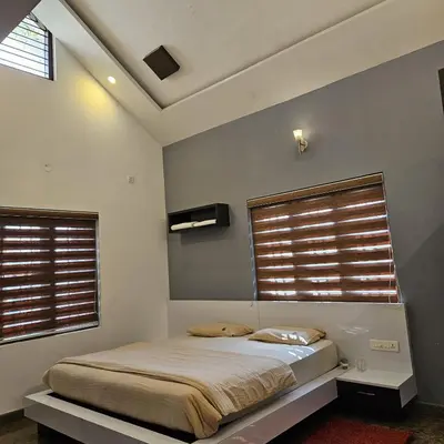 a bedroom with a bed and two windows at Bridge Point Home Stay in Kushālnagar
