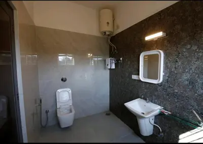 a bathroom with a toilet and a sink at Bridge Point Home Stay in Kushālnagar