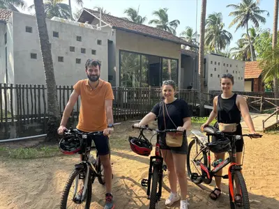 three people standing with their bikes in front of a house at Thira Beach Home in Thanniyam