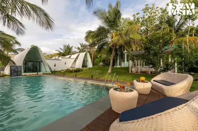 a resort swimming pool with chairs and a tent at StayVista at Shwaas 4BR Mysore with Private pool and landscape in Mysore