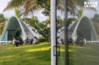 a group of people sitting on benches in front of two domes at StayVista at Shwaas 4BR Mysore with Private pool and landscape in Mysore