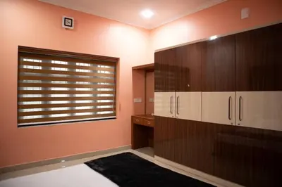 a bathroom with brown cabinets and a large window at Jaalakam Retreat in Trichūr