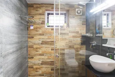 a bathroom with a shower with a toilet and a sink at Jaalakam Retreat in Trichūr