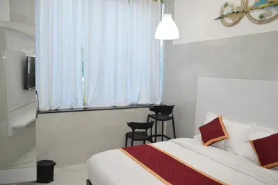 a bedroom with a bed with two chairs and a window at M Grand Stay in Coimbatore