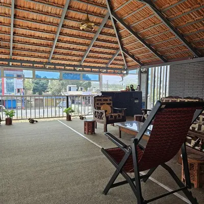 a patio with two chairs and a table and a balcony at MysticGreens Guest House! in Kushālnagar