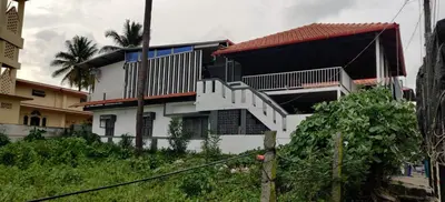 a white house with a staircase in front of it at MysticGreens Guest House! in Kushālnagar