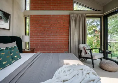 a bedroom with a bed and a brick wall at LohonoStays Villa Amani 8A in Coonoor