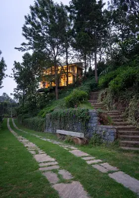 a house on the side of a hill with a bench at LohonoStays Villa Amani 8A in Coonoor