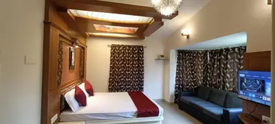 a bedroom with a bed and a couch and a television at Quick Sort Residency in Ooty