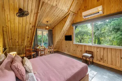 a bedroom with a bed and a window and a table at The Cove Lakkidi in Vythiri